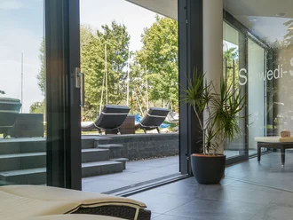 Ruhebereich mit Panoramafenstern und Zugang zur Sonnenterrasse im Hotel Schwedi – entspannen mit Ausblick ins Grüne.