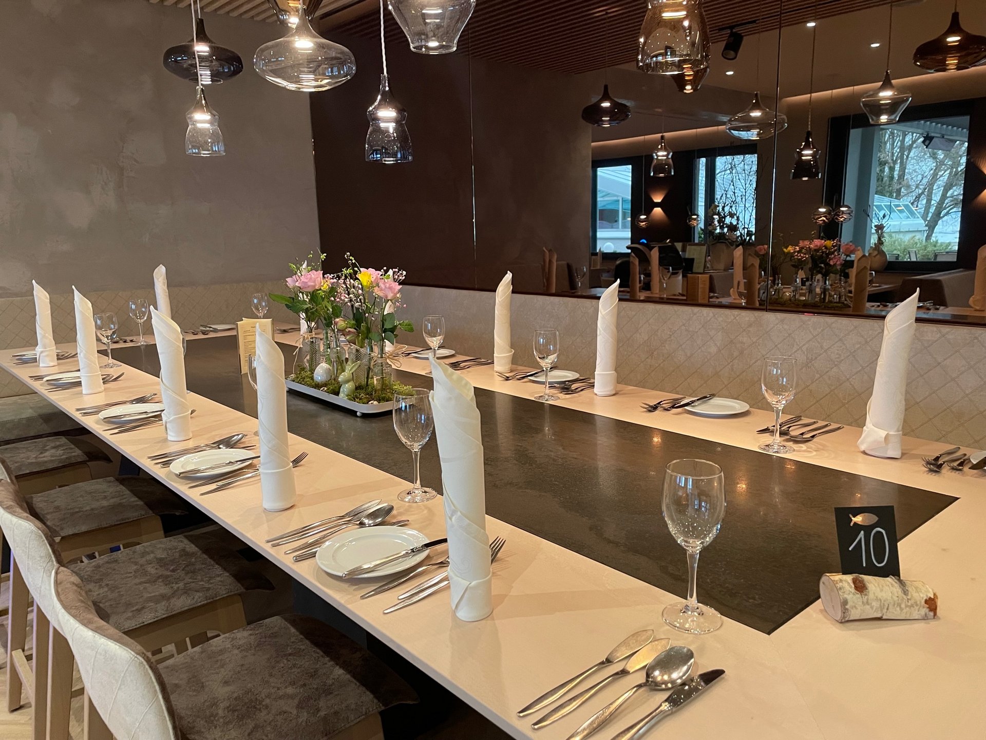 Eine gedeckte Tischtafel im Restaurant des Hotel Schwedi. In der Mitte des Tisches steht eine österliche Blumendekoration.